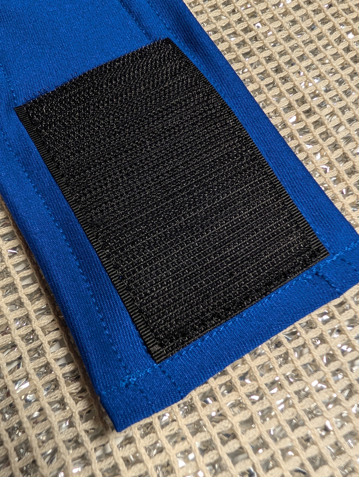 Close-up of a blue fabric belly strap with a large black hook-and-loop patch, laid on Chillybuddy's cotton mesh.