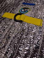 Close-up of a silver reflective mesh fabric with a bright yellow webbing strap and a black D-ring for hardness.